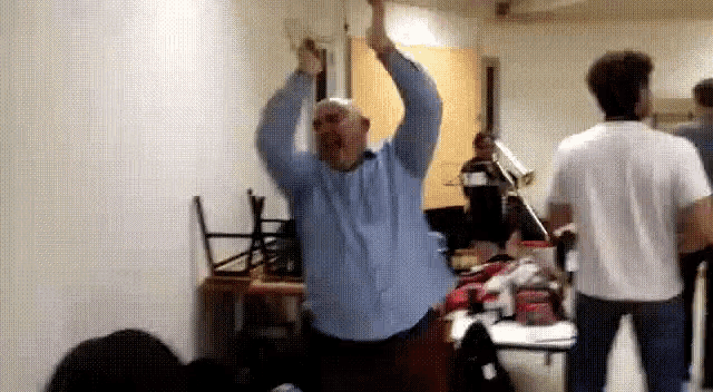 a man in a blue shirt with his arms in the air