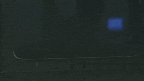 a person is sitting in a dark room looking out a window with a blue bag on their head