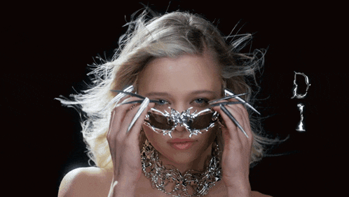 a woman with long nails is wearing sunglasses and a necklace that says di
