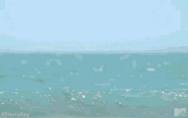 a shirtless man is standing in the ocean looking at the camera .