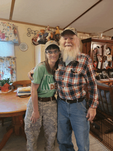 a man and a woman are posing for a picture and the woman is wearing a green shirt that says " i love my country "