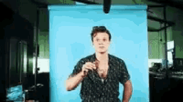 a man in a black shirt is standing in front of a blue wall .