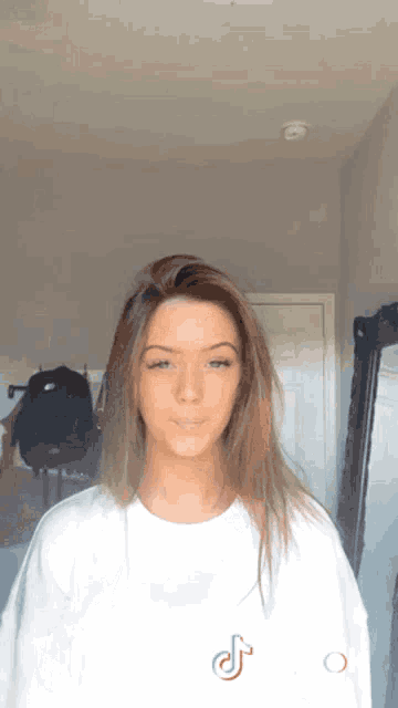 a girl wearing a white t-shirt with a tik tok logo on it