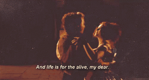 a man and a woman are dancing in front of a fireplace with the words `` and life is for the alive my dear ''