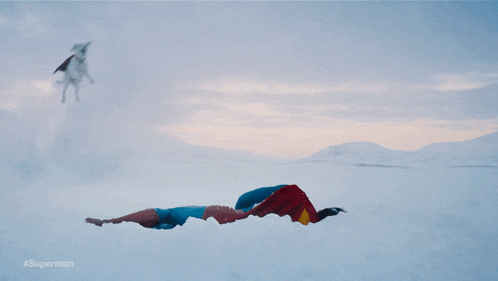 a man in a superman costume is flying through the air in the snow