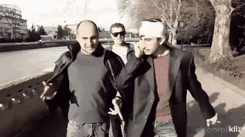 a man with a bandage on his head talks on a cell phone while walking with two other men .
