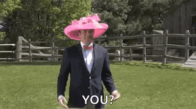 a man in a suit and bow tie is wearing a pink hat and a pink bow tie .