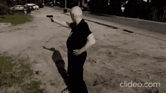 a man in a black shirt is pointing a gun at the camera with clideo.com at the bottom of the screen