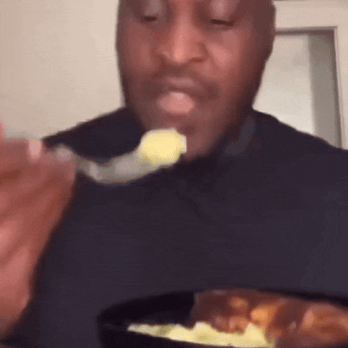 a man is eating a spoonful of food from a bowl of food .