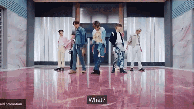 a group of men are dancing in a room with a sign that says what on it