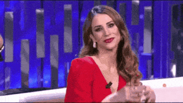 a woman in a red dress is sitting in a chair with a microphone .