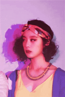 a woman wearing a headband and a necklace is looking at the camera