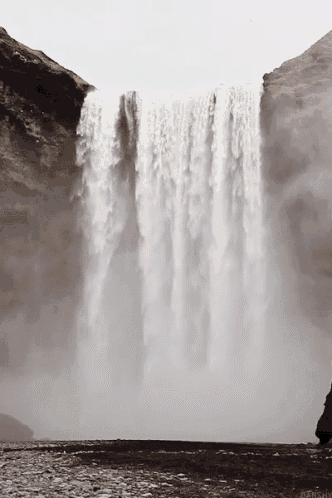 a waterfall is surrounded by rocks and a cliff