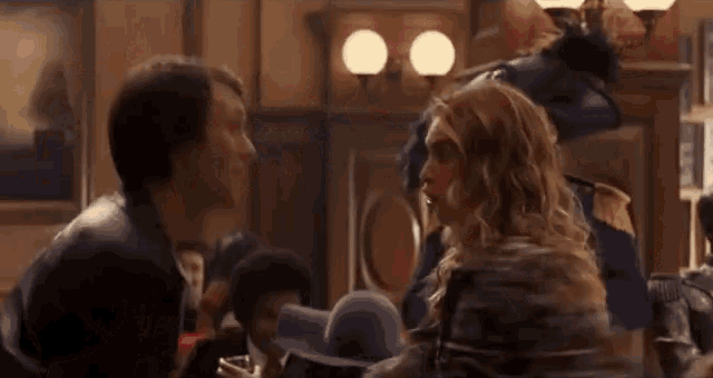 a man and a woman are fighting in a crowded room in a restaurant .