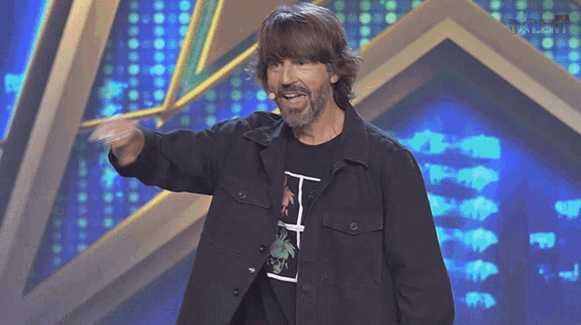 a man wearing a black jacket and a black t-shirt with the letter h on it