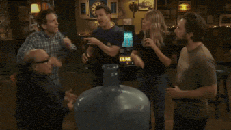 a group of people are standing around a large water cooler .