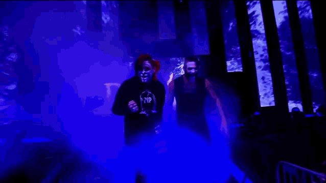 a man and a woman are standing in a dark room and the woman is wearing a shirt that says rip