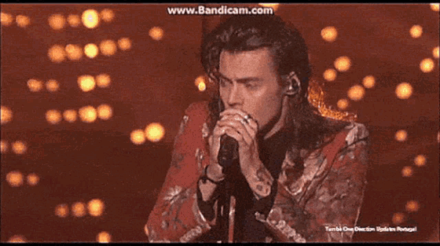 a man with long hair singing into a microphone with the website www.bandicam.com in the upper right corner