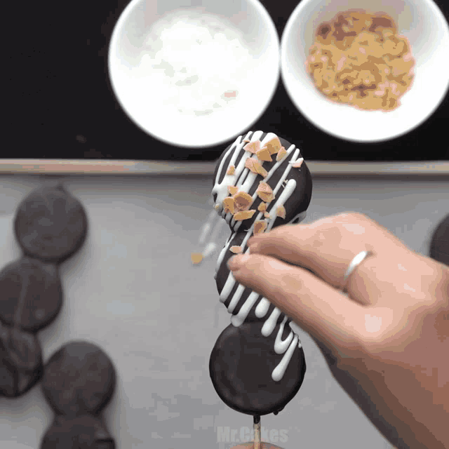 a person is decorating a chocolate covered cookie with nuts and icing