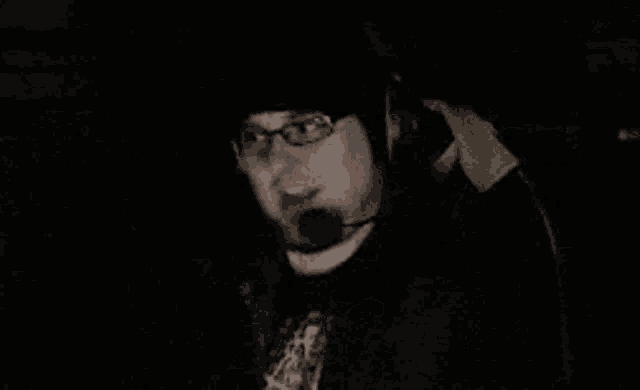 a man with glasses and a hat is wearing headphones and a microphone .