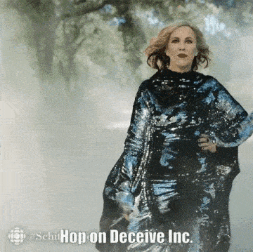 a woman in a blue sequined dress is walking down a foggy street .