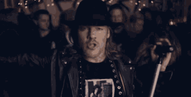 a man in a hat is singing into a microphone in front of a crowd