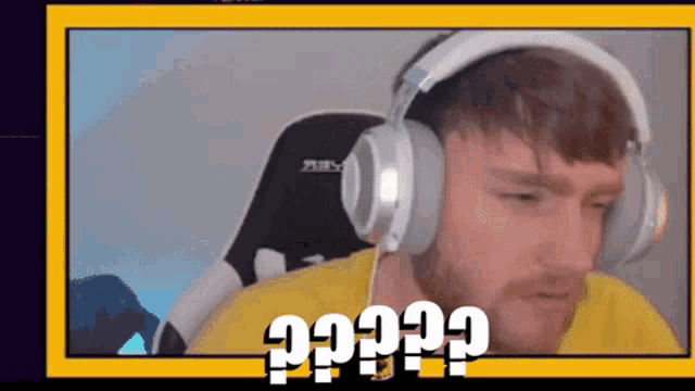 a man wearing headphones and a yellow shirt is sitting in front of a screen that says ?