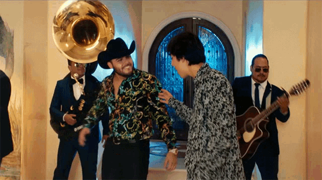 a man in a cowboy hat is standing next to a man in a floral shirt