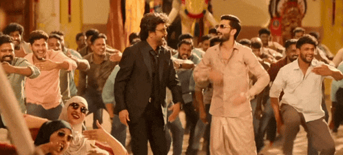 a group of people are dancing in a room and one of them is wearing sunglasses
