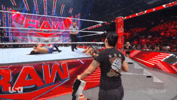 a man is standing in front of a wrestling ring with the word raw on it