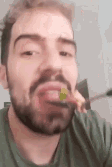 a man with a beard is eating a piece of pizza with a spoon .