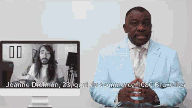 a man in a light blue suit is talking to a man in a black and white photo