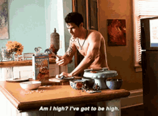 a shirtless man is standing at a kitchen counter with a box of frosted flakes behind him