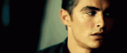a close up of a man 's face with a serious look on his face in a dark room .