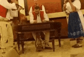 a group of people playing instruments including a man sitting at a table