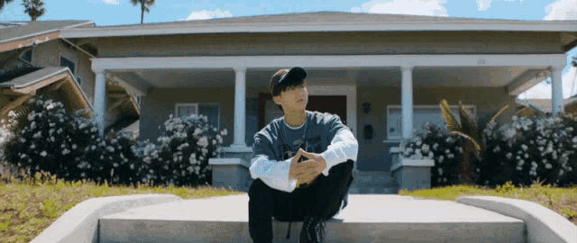 a man sitting on the steps of a house wearing a t-shirt that says i love you