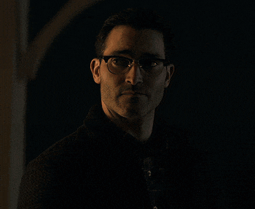 a man wearing glasses and a black jacket stands in the dark