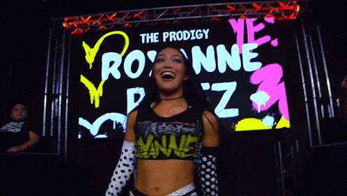 a woman stands in front of a large screen that says the prodigy