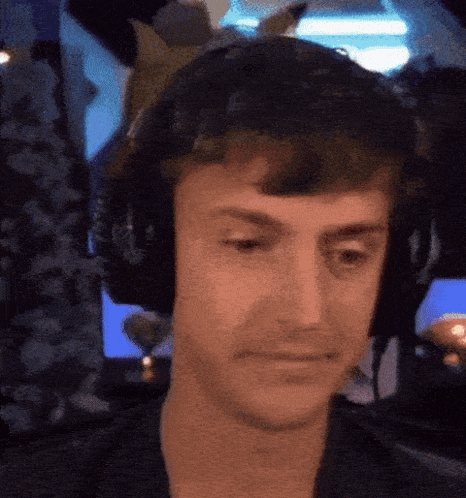 a man wearing headphones looks at the camera with a serious look on his face