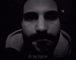 a man with a beard is looking at the camera in a black and white photo with the word furoxos on the bottom right .