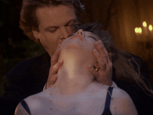 a man kissing a woman 's neck with a ring on his finger