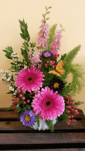 a vase filled with pink and purple flowers with a butterfly on top