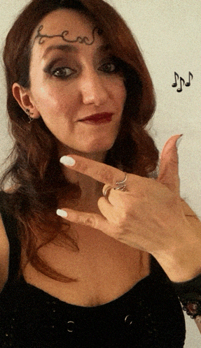 a woman with a tattoo on her forehead holds up her fingers
