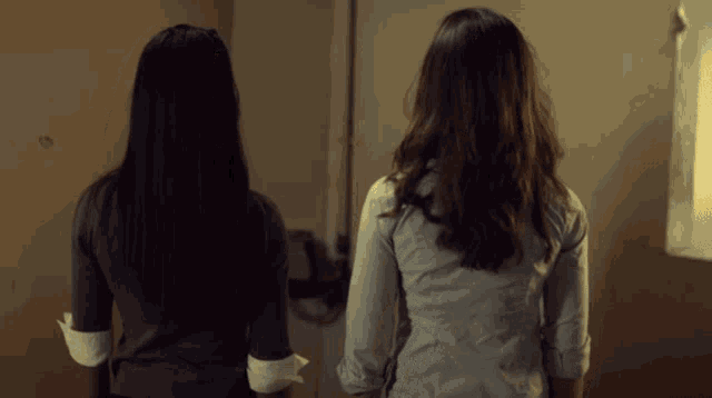 two women standing next to each other in a bathroom