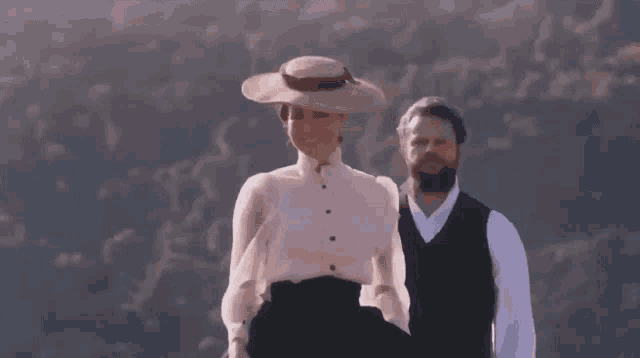a man and a woman are standing next to each other on a hill .