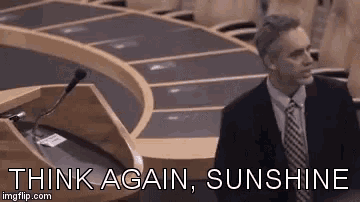 a man in a suit and tie is standing in front of a podium with the words think again sunshine .