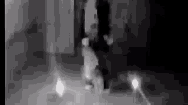 a black and white photo of a person standing in a dark room with candles .
