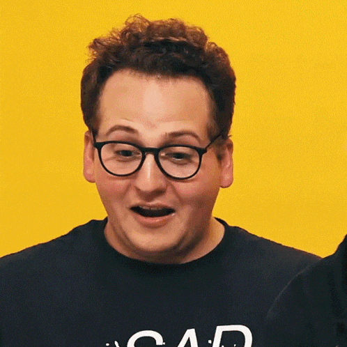 a man wearing glasses and a black shirt that says sad on it