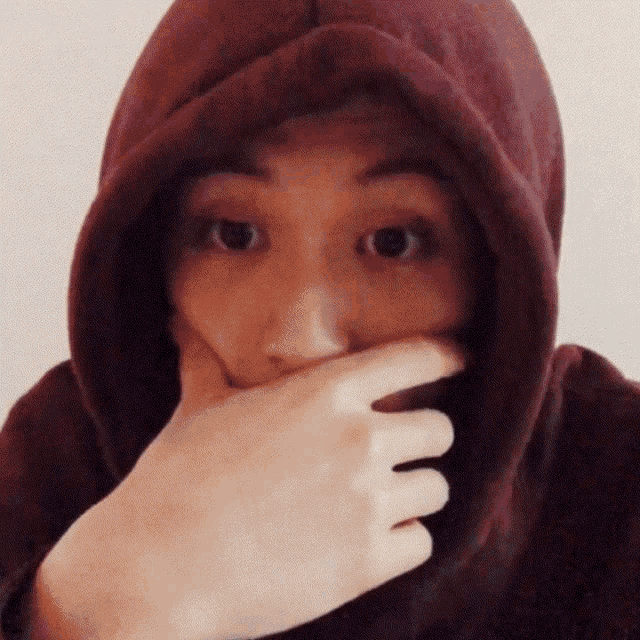 a person wearing a maroon hoodie covering their mouth