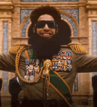 a man with a beard and sunglasses is standing in front of a microphone with his arms outstretched